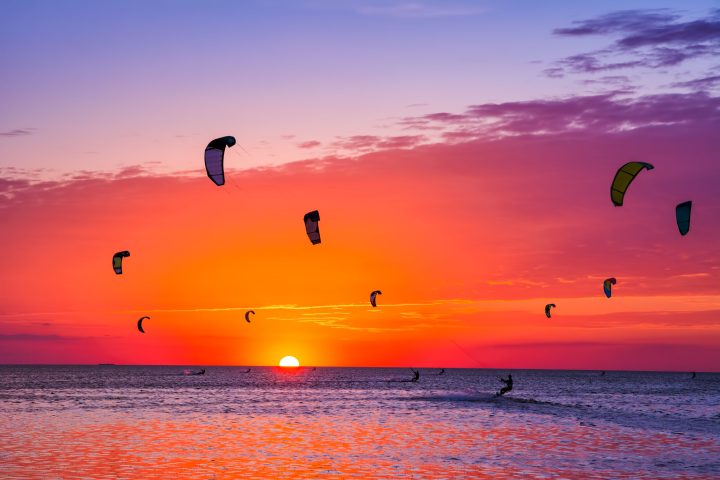 a group of people flying kites on a beach